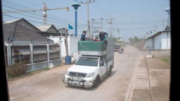 Maeklong Railway parallel zur Straße in Dörfern