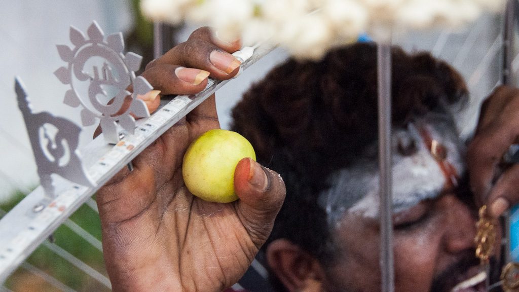 Durchstoßen der Zunge mit einem Metallstab als Vorbereitung für Thaipusam in Singapur